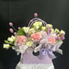 An assortment of small, dainty flowers styled to fit a bag-shaped vase.
