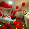 Habitacion romantica con petalos de rosa roja, globos, senal de i love