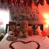 Habitacion decorada con petalos rojos, globos con helio, globos, oso de peluche