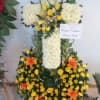 Arreglo funebre en forma de cruz elaborado con flores blancas, lirios naranjas