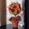 A miniature autumn tree arrangement featuring a harmonious fusion of fall hues.