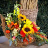 Fresh fall flowers, gourds and pumpkins designed in a wicker cornucopia. 