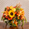 Sunflowers, roses, and other seasonal autumn florals in a glass vase. 