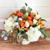 White hydrangeas with greenery and roses and other small flowers with a