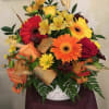A DECORATIVE STONE CONTAINER, FILLED WITH BRIGHT FALL FLOWERS, WHEAT AND COLORFUL