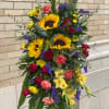 Honor a bright, beautiful life with this lovely burst of sunflowers, carnations