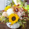 White ceramic pumpkin filled with seasonal blooms and accents