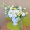 A fresh all white arrangement including garden roses and orchids comes in