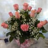 12 Roses arranged in a vase with beautiful greens and accented with