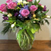 ASSORTED PINKS, GEEN AND PURPLE BLOOMS, ARRANGED IN A VASE.