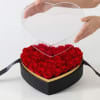 Black heart-shaped acrylic box with golden details full of red roses.