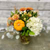 White hydrangea, fall mums, hypericum berries and mini pumpkins nestled in a