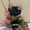 A bud vase filled with a silk black rose and filled with