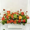 A radiant mix of orange and golden roses, accented with playful chamomile