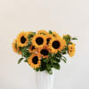 An elegant arrangement of fresh sunflowers designed in a white vase, bringing