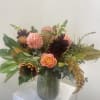 Bronze and Clover colored flowers in a generous sized vased. Flowers may