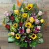 A gorgeous one sided arrangement with roses, lilies, sunflowers, and birds of