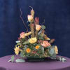 A mix of fall colored flowers and greenery in a low design