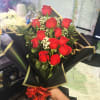 12 beautiful long stem red roses in a bouquet with greenery and