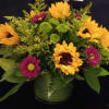 This sunflower arrangement is accented with green buttons purple daisies 