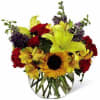 A clear glass container filled with an assortment of fall toned flowers.