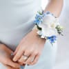 Pearl bracelet corsage featuring a white phalaeonopis orchid, accented by blue delphinium