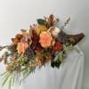 A dark wicker cornucopia featuring a cascade of fall blooms and texture.