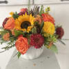 
A radiant mix of autumn blooms bursts from a charming white pumpkin