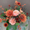 A beautiful ceramic pumpkin filled with a beautiful selection of fall flowers.