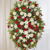 One-sided standing spray arrangement with red roses, carnations and hypericum, white Asiatic