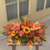 centerpiece featuring red daisies , orange canations, lilies, and sunny sunflowers. his