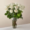 A classic bouquet of white roses arranged in a tall, clear glass