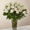 A classic bouquet of white roses arranged in a tall, clear glass