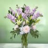 This arrangement has lavender stock, white lilies, cremons, hydrangeas, and greens in