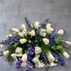 Casket spray of white roses, blue delphinium, and carnations. Customize with more