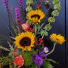 This mixed stylized arrangement features sunflowers and other seasonal blooms perfect for