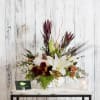 An elegant white pumpkin container is filled with a modern autumn palette