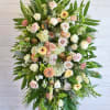 This elegant spray filled with lush greenery and soft seasonal blooms, offers