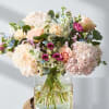 Blush pink hydrangeas and peach roses create a delicate, romantic feel in