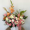 An elegant mix of roses, gladiolus, and dahlias in warm coral and
