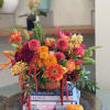 Flowers: orange roses, burgundy spray roses, orange zinnia, seasonal dahlias, orange waxflower