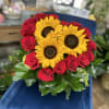 Three sunflowers arranged in the shape of a heart, accented with roses