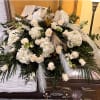 A beautiful casket spray with white roses, hydrangeas, stock, and assorted greens.