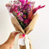 A modern dried flower bouquet in vibrant shades of pink and magenta