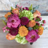 A low and wide cylinder vase filled with bright coral, green and