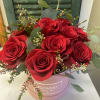 A dozen red or pink roses arranged low and compact in a