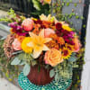 A fall themed bouquet arranged in a glass pumpkin