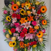Funeral spray filled with a colorful array of lilies, sunflowers, roses, carnations