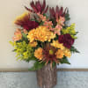 This vibrant arrangement features rich burgundy carnations, golden chrysanthemums, and orange alstroemeria