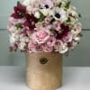 Soft pastel roses, dramatic burgundy orchids, and white anemones create an enchanting